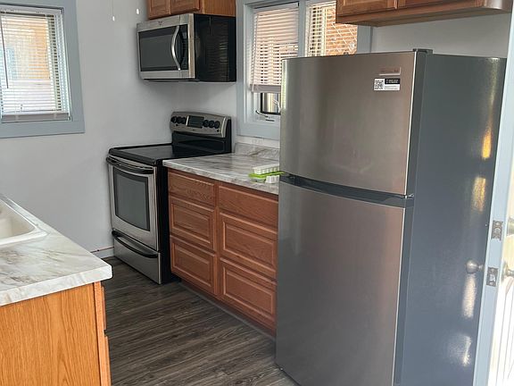 Stove, microwave and refrigerator, more cabinets and open countertop space. Task lighting above sink.