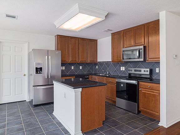 Kitchen bar, kitchen island with tile back splash and stainless steel appliances
