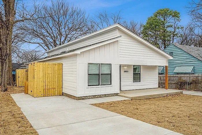 A sleek, modern bungalow featuring a white board-and-batten facade, asymmetrical roofline, and clean concrete driveway.