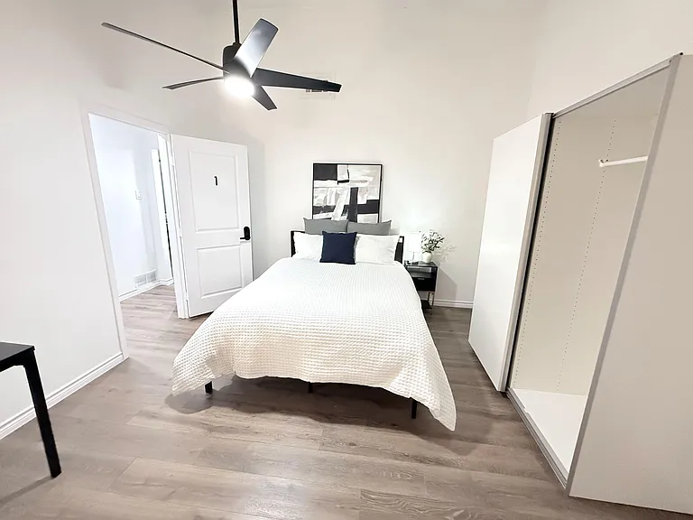 Large luxurious room with a large window and big close with sliding doors, standing mirror, desk and chair.