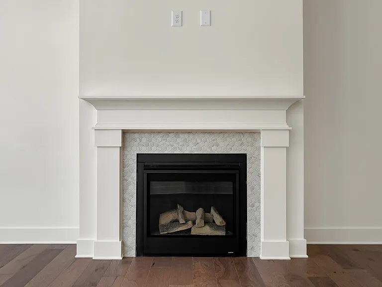 The centered fireplace with gas logs is surrounded by 8" neutral hexagon tile.
