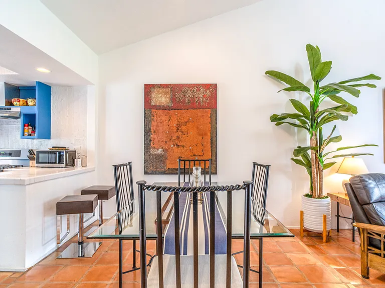 Open dining area with Saltillo tile floors, glass-top table, and seamless flow to the upgraded kitchen and living room. Bright, airy layout designed for easy entertaining and relaxed desert living.