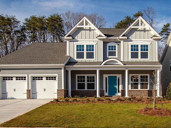 A large house with two garages and a blue door is sitting on top of a lush green lawn.