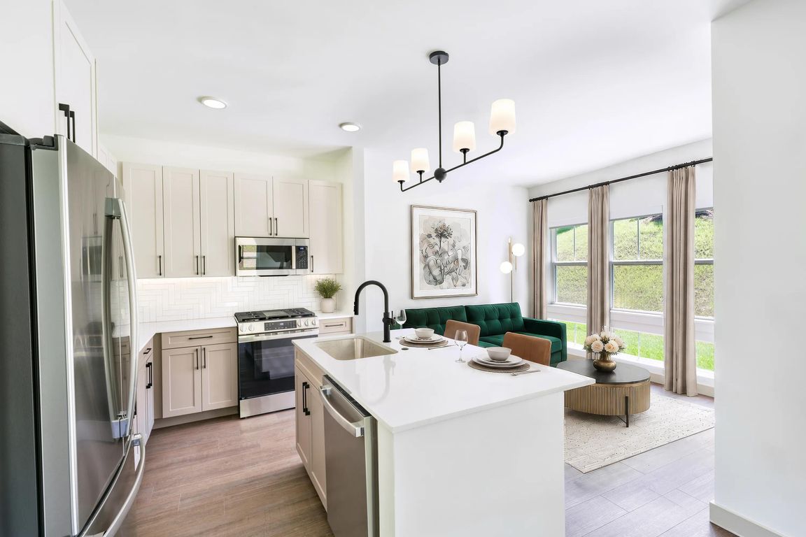 Open kitchen with a generous island, quartz surfaces, and oversized windows that bring natural light into the heart of the home.