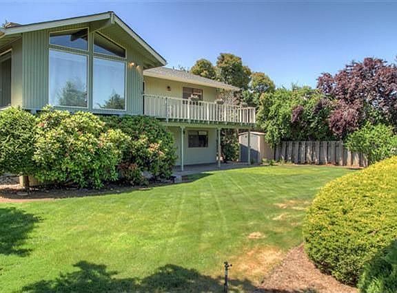 This view is of the back of the home, showcasing the beautiful living room windows. This is half of the backyard, as it terraces down one more level.