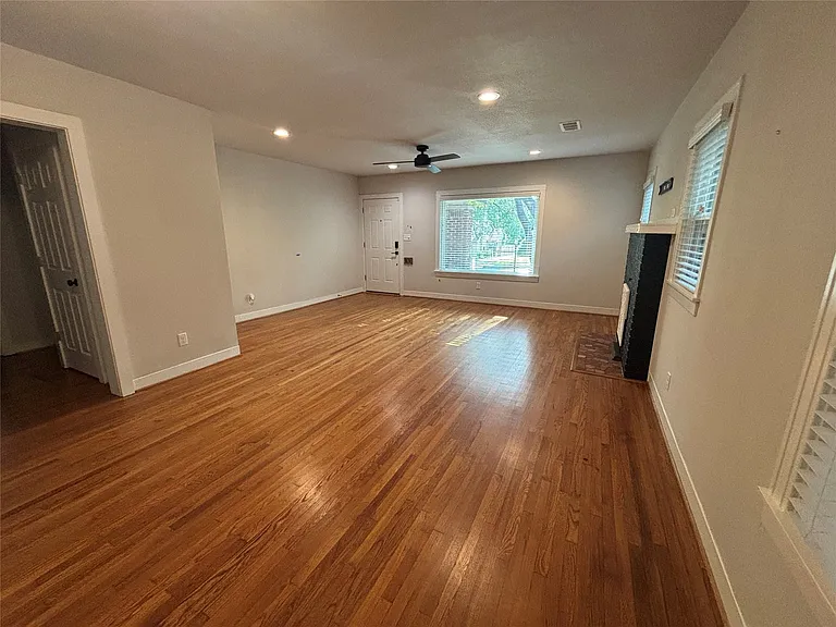 Spacious living area featuring wood-finish flooring, recessed lighting, and a ceiling fan