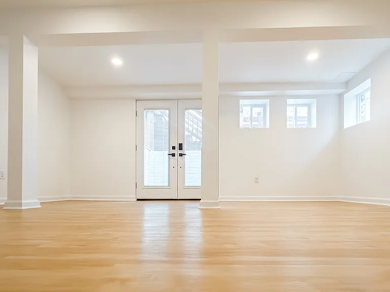 Private enclosed three-season room with French doors, multiple windows, updated flooring, and bright natural light.
