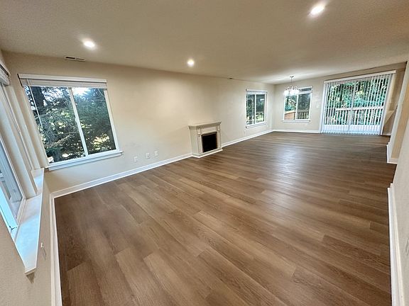 Spacious living room with lots of lights with brand new vinyl flooring and wooden blinds.