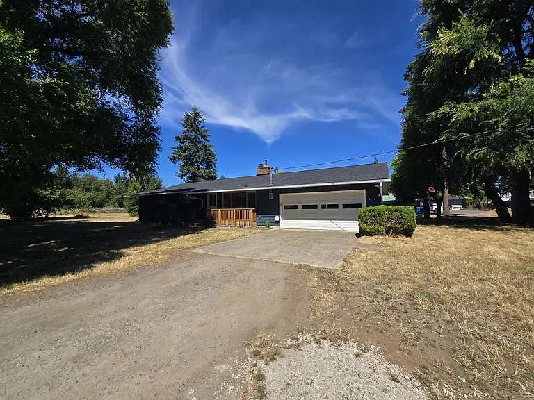 Single level home with driveway and large front yard