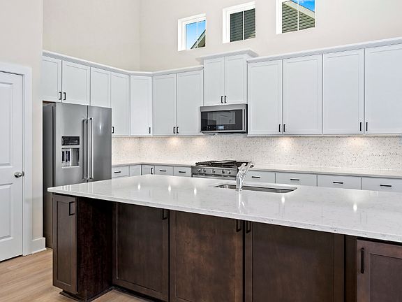 Kitchen with large island, white cabinets, vaulted ceiling and 3 clerestory windows in a DRB Homes L