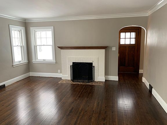 Open concept living room and dining room with original crown molding and wood burning fireplace