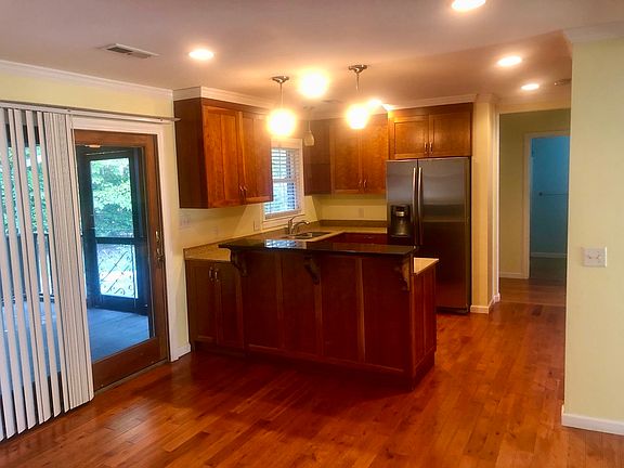 Partial view of the kitchen. There's a downdraft stove below the eat in bar. Stainless steel appliances. There's another long counter in kitchen (not pictured) on the other side of the walkway through kitchen.
