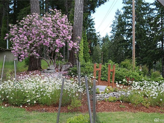 Fun landscaping in front with fountain, bridge and rock river.