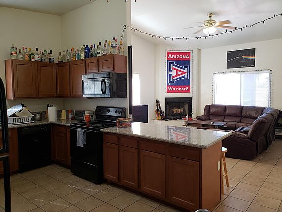 Granite kitchen with 2 fridges open to the living room with tall ceilings.