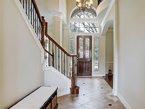 The stunning foyer has an decorative door, side windows nd even double windows over the door for an elegant entry. There is double crown molding details and soaring 20 foot ceiling.