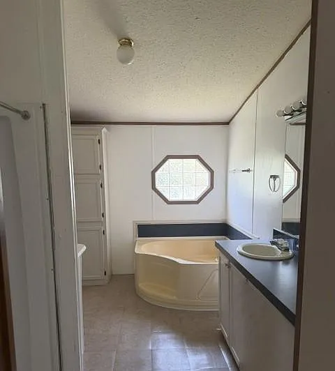 Spacious full bathroom with a corner soaking tub, wide vanity counter, and built-in storage for toiletries and linens.