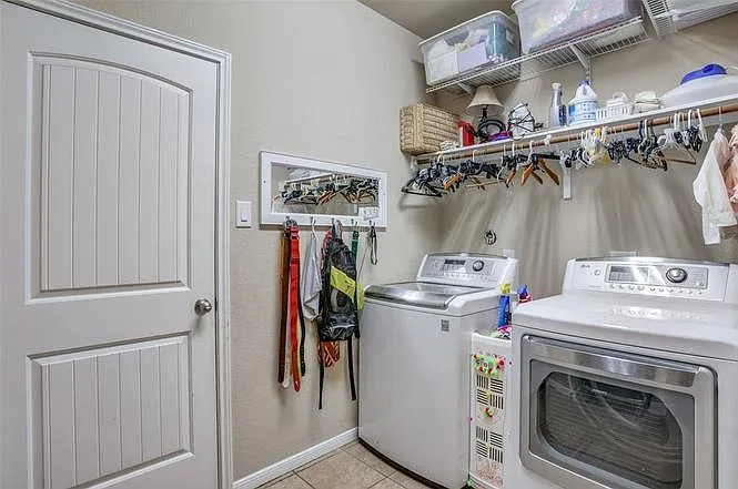 Dedicated laundry room with full-size washer and dryer plus wall-mounted shelving and hanging space for easy organization.