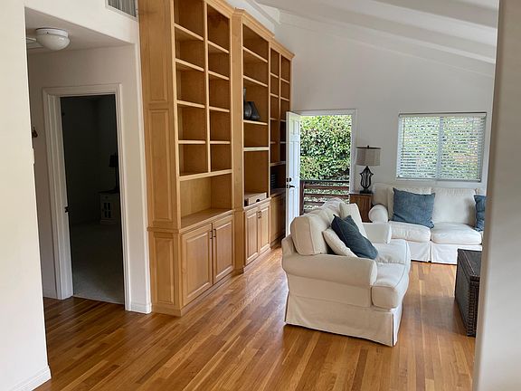 Family room with bookcase, hardwood floors, door to bedroom.
