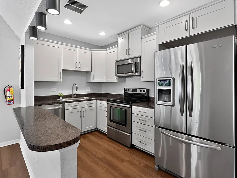 Enjoy a clean, modern community kitchen featuring stainless steel appliances and crisp white cabinetry at Renaissance at Carol Stream in Carol Stream, IL.
