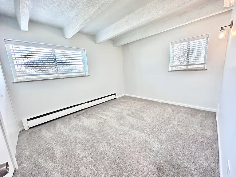 Bright and spacious empty room with large windows, plush carpet, and modern light fixture. Bright and spacious empty room with large windows, plush carpet, and modern light fixture.