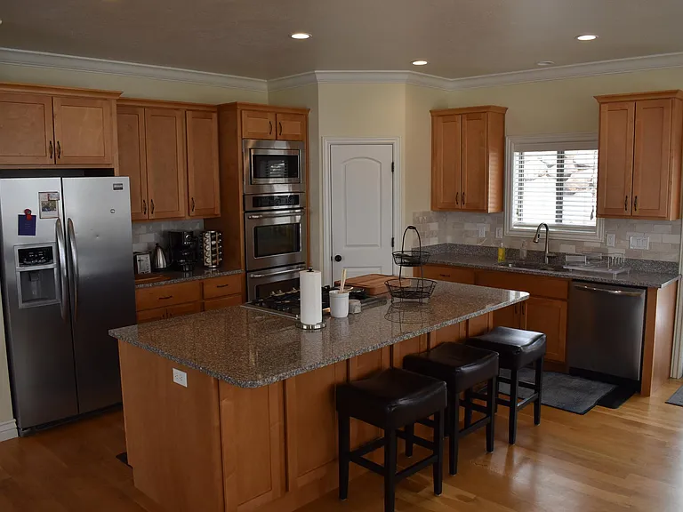 The fully furnished kitchen boasts a double oven, gas range, toaster, coffee station, spices, pots, pans, utensils, and sharp knives. It includes ample empty cupboard space for storage, providing everything you need for a seamless cooking experience.
