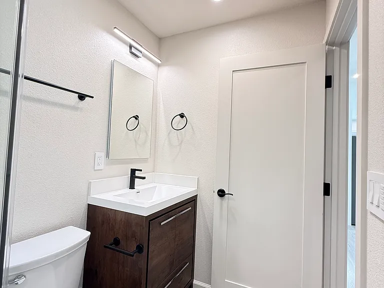 Hallway full bathroom with skylight and shower finished in frameless enclosure.