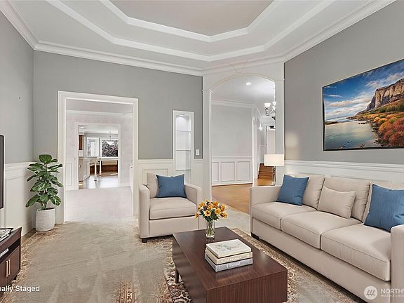The formal living room features wainscoting, coved ceiling, new carpet, built-in display case with lighting and easy access to the dining room.>