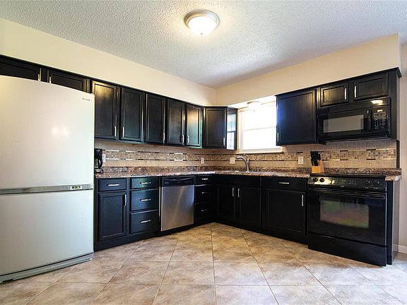 This spacious newer kitchen, features an abundance of striking cabinetry, stainless appliances, and custom tile backsplash.