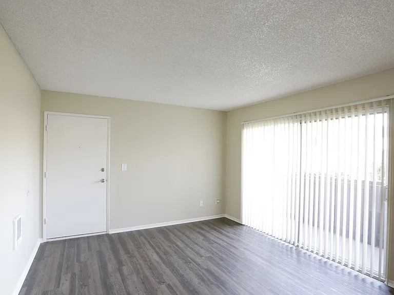 Living room with front door and sliding glass doors to private porch at Villa Pacific Apartments in Oceanside, California.
