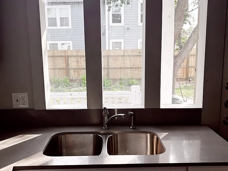 View from kitchen to fenced in backyard. New windows give this apartment a modern feel.