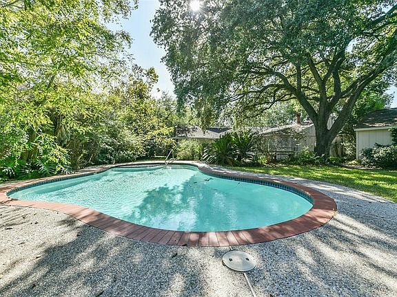 The beautifully shaped pool is embedded in lush greenery.