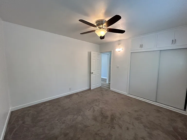 Bedroom with ceiling fan and carpet.