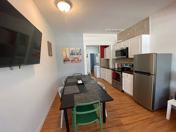 Bright dining room with 6 chairs and their respective placemats and TV