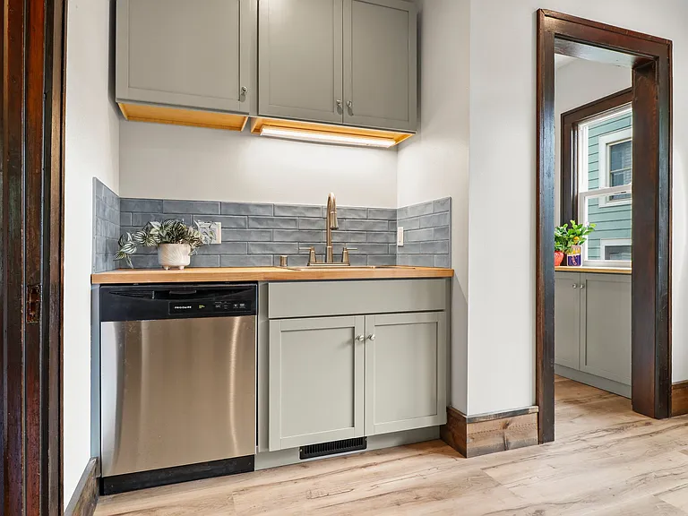 Bottom unit: Good photo of the sink and dishwasher leading to the butler pantry and dining area to the right. The door at the left leads to the hallway between bedrooms.