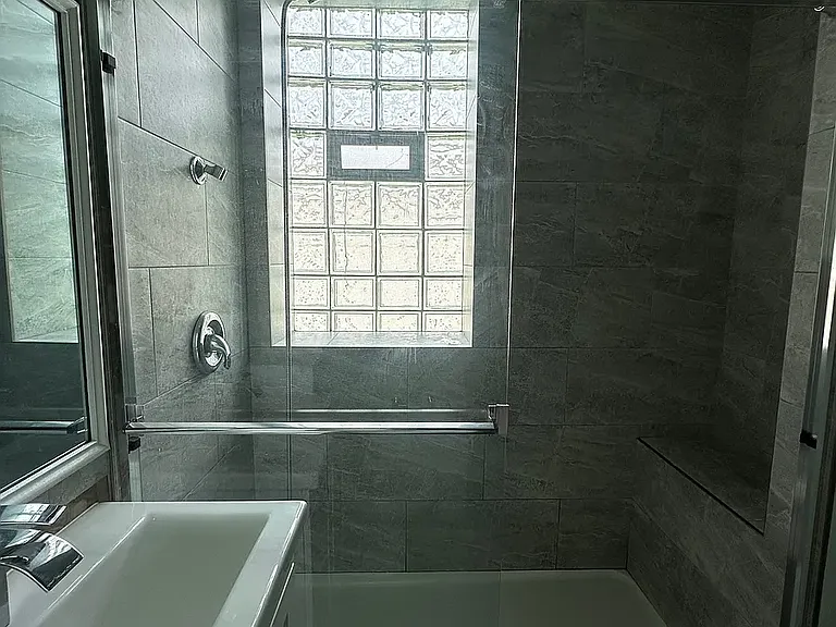 Standing shower with ledge to sit inside.