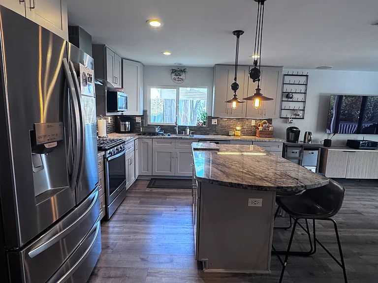 The kitchen features a gas range, stainless steel appliances and a large center island.