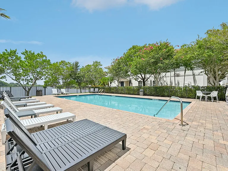 Inviting outdoor pool area with comfortable loungers, surrounded by lush greenery and serene views.