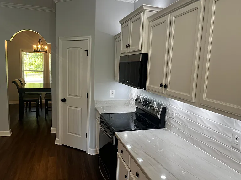 Kitchen cooking area with stainless steel appliances, tile backsplash, and generous counter space.