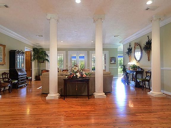 Guests enter from the expansive covered front Porch and witness this impressive view of the Foyer that is set beneath an  arched ceiling and where hardwood floors flow graceful to the Living Room