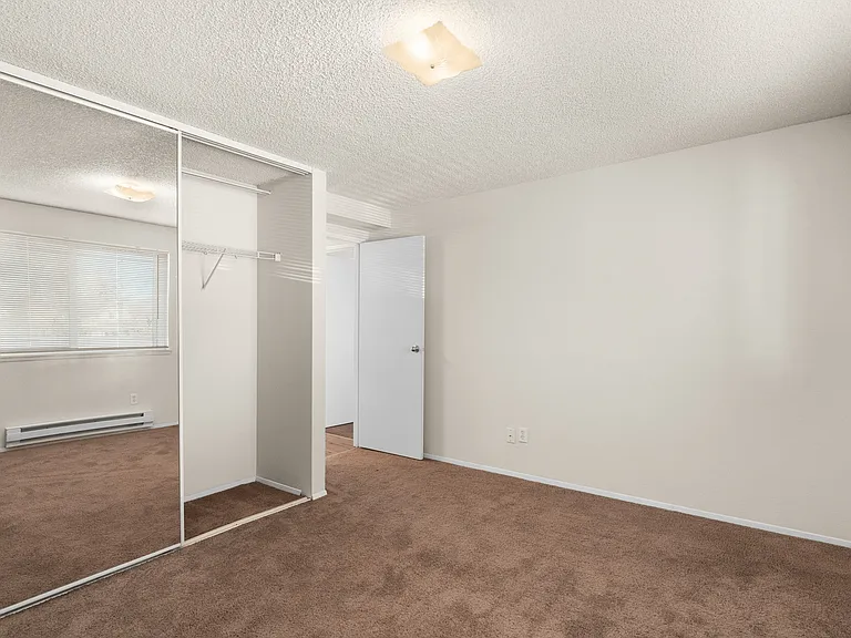 Bright, spacious bedroom with large window, mirrored closet doors, and plush carpet. Bright, spacious bedroom with large window, mirrored closet doors, and plush carpet.