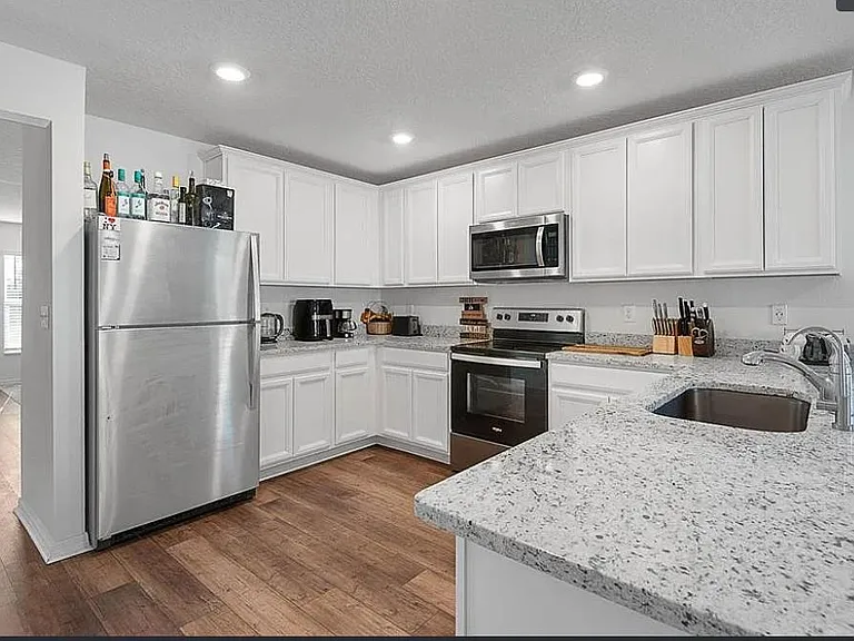 Updated kitchen with white cabinetry, granite counters, and stainless-steel appliances plus a spacious prep peninsula.