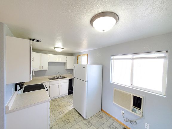 Kitchen and dining room with flat-top electric range, dishwasher, vent hood and refrigerator.