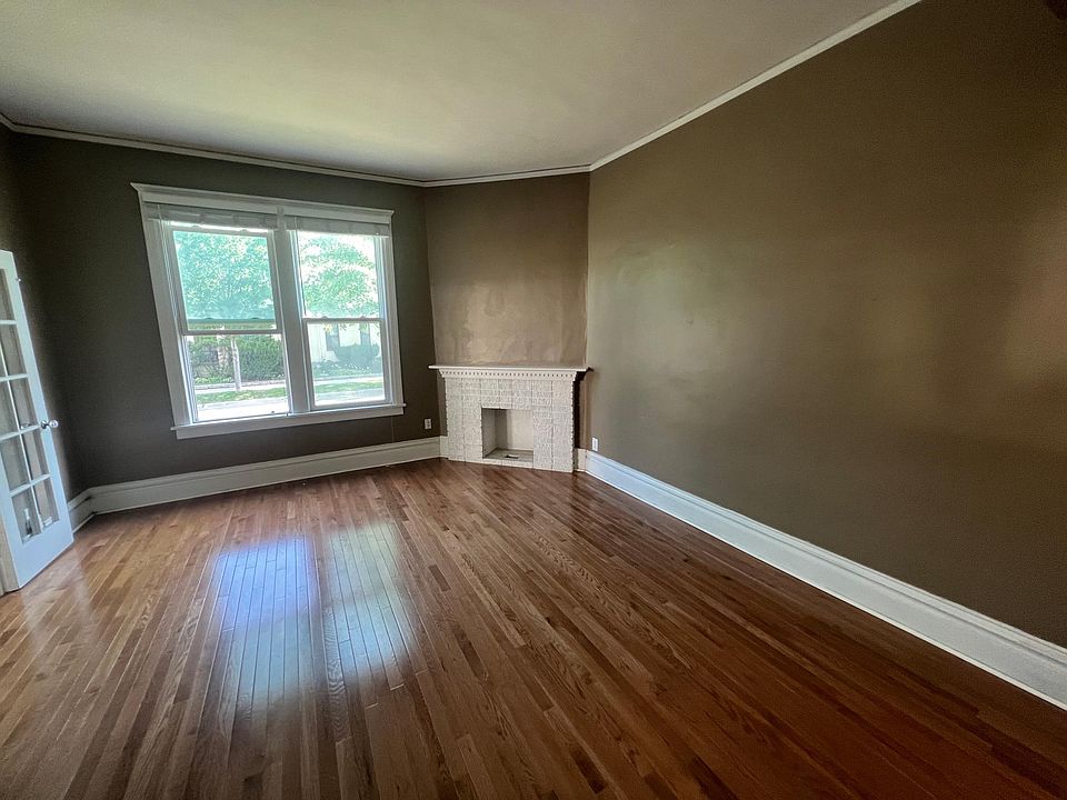 Large living room with 10 foot ceilings, oak hardwood floors, crown moldings, tall baseboards, and decorative fireplace