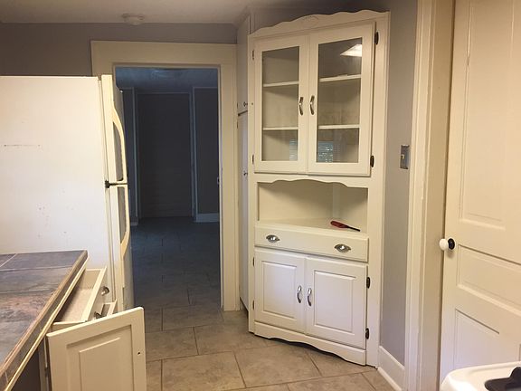 Kitchen with refrigerator and built-in corner cabinet and pantry.