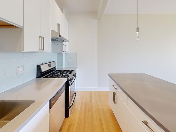 Kitchen with multiple cabinets, stove, range hood, and sink