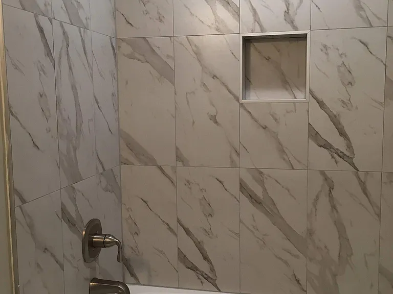 Hall bath shower tub with shampoo cubby in the wall.