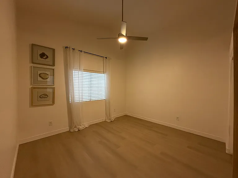Bright secondary bedroom with large window and neutral finishes.