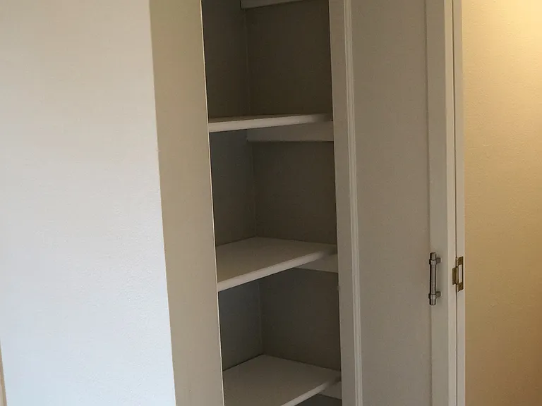 Hall linen closet with wood bi-fold door.