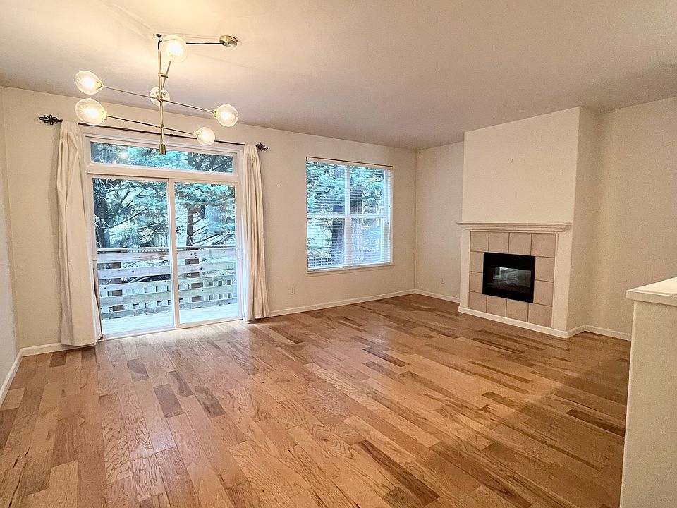 Living room, with wood floors and fireplace. Sliding door to yard. Open to kitchen.