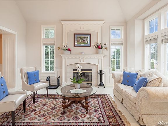 The formal living room features marble slab flooring, extensive windows, and a wood-burning fireplace with a marble surround complimenting the marble floor.